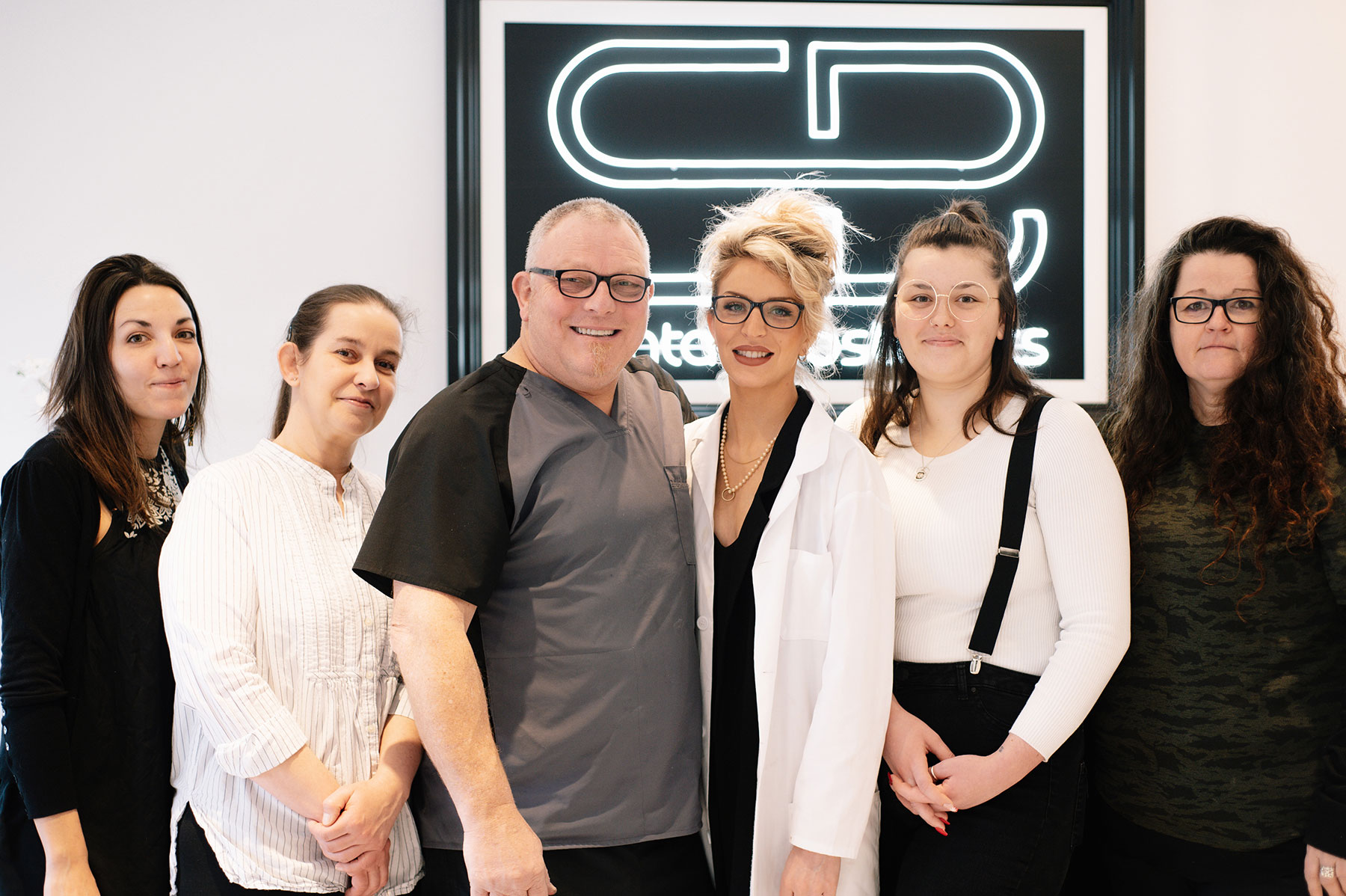 Meet the team at SB Denture clinic posed for a group photo in front of the receptionist desk